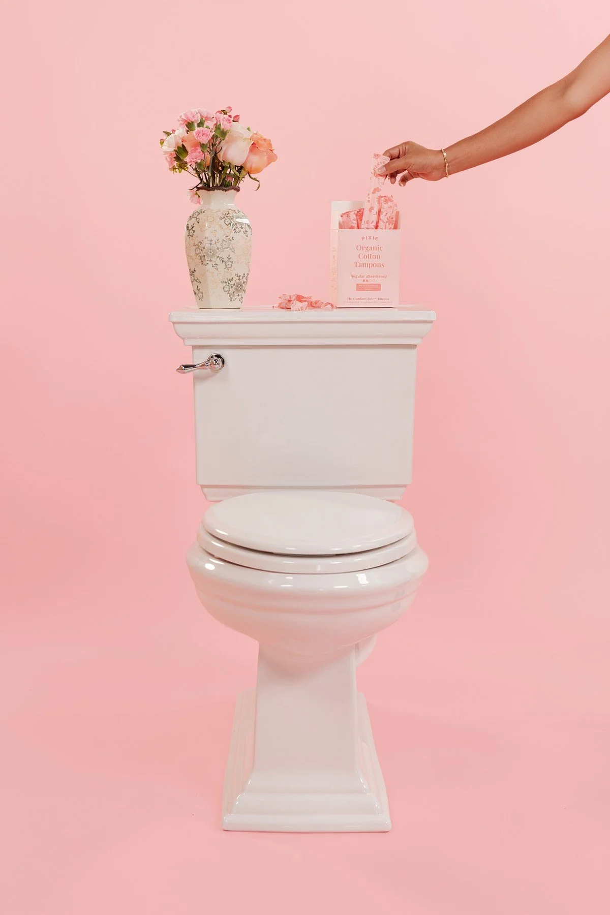Pixie Cup product setup with a white toilet and pink backdrop