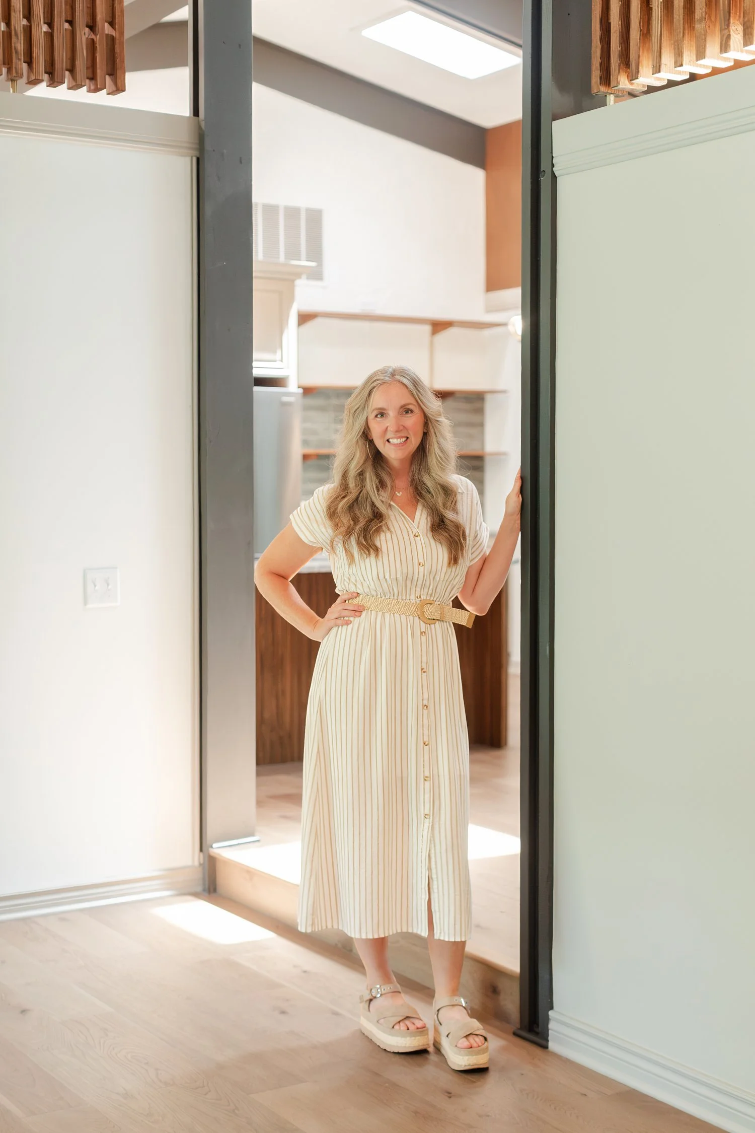 Real estate agent in a striped shirt dress standing in a doorway with one hand on a hip, full length headshot in Bolivar, MO