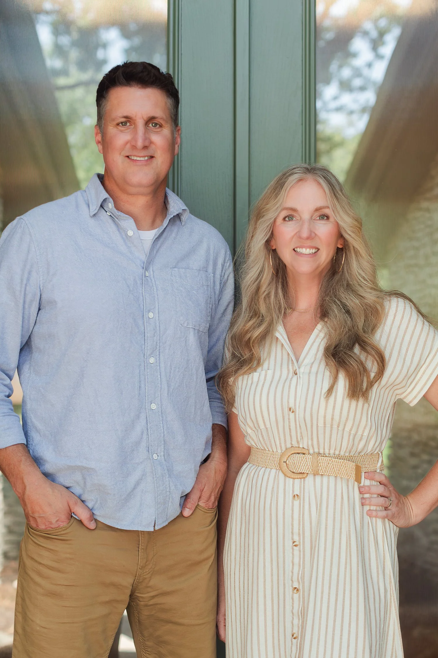 Two real estate agents in chambray and a cream striped dress at a green front door, team headshots in Bolivar, MO
