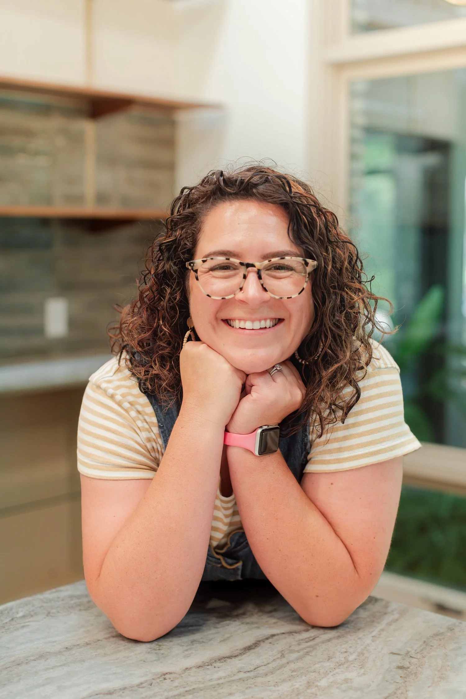 Real estate agent in glasses resting chin on hands at a stone counter, real estate agent headshots in Bolivar, MO