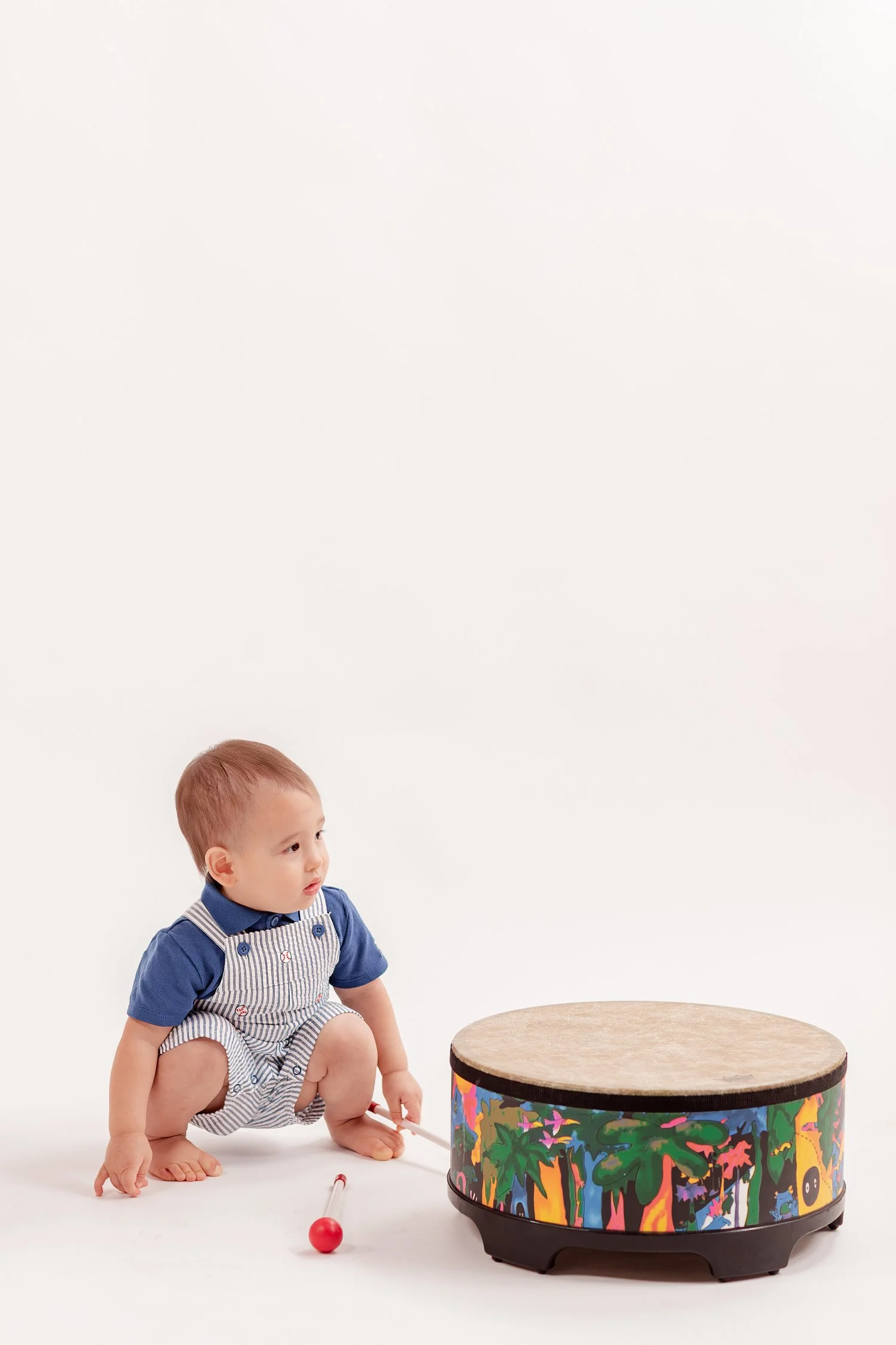Winston sitting on the white studio floor beside his drum