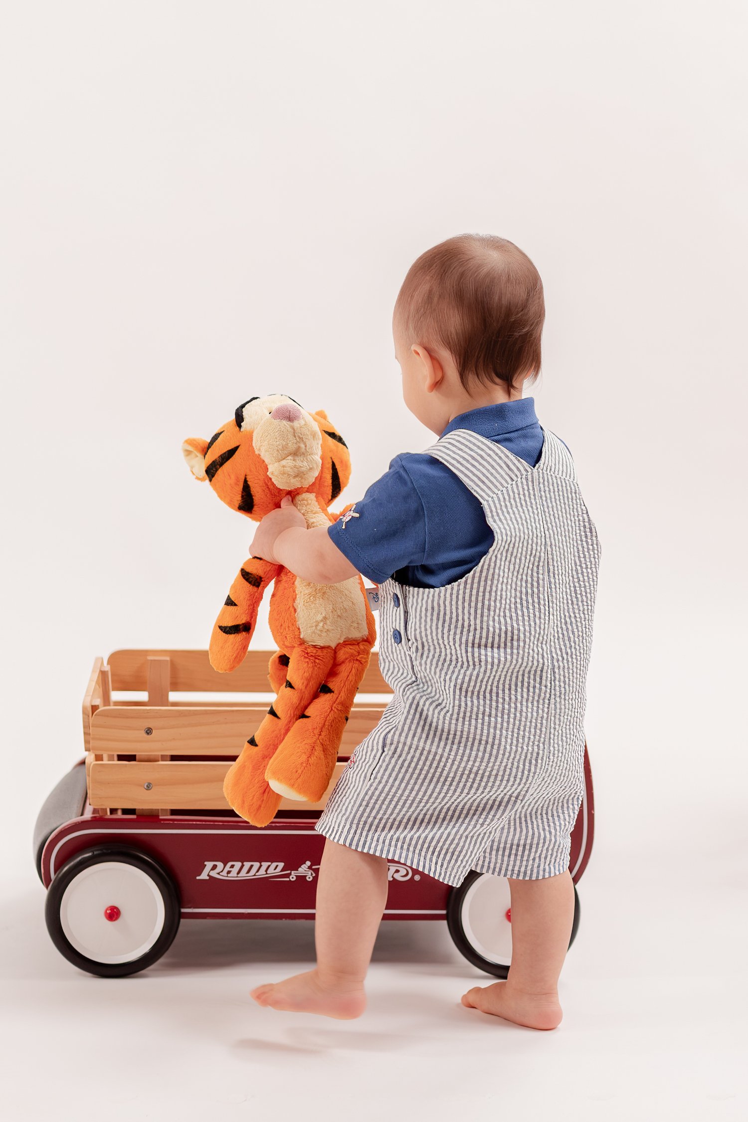Winston holding Tigger beside his red wooden wagon