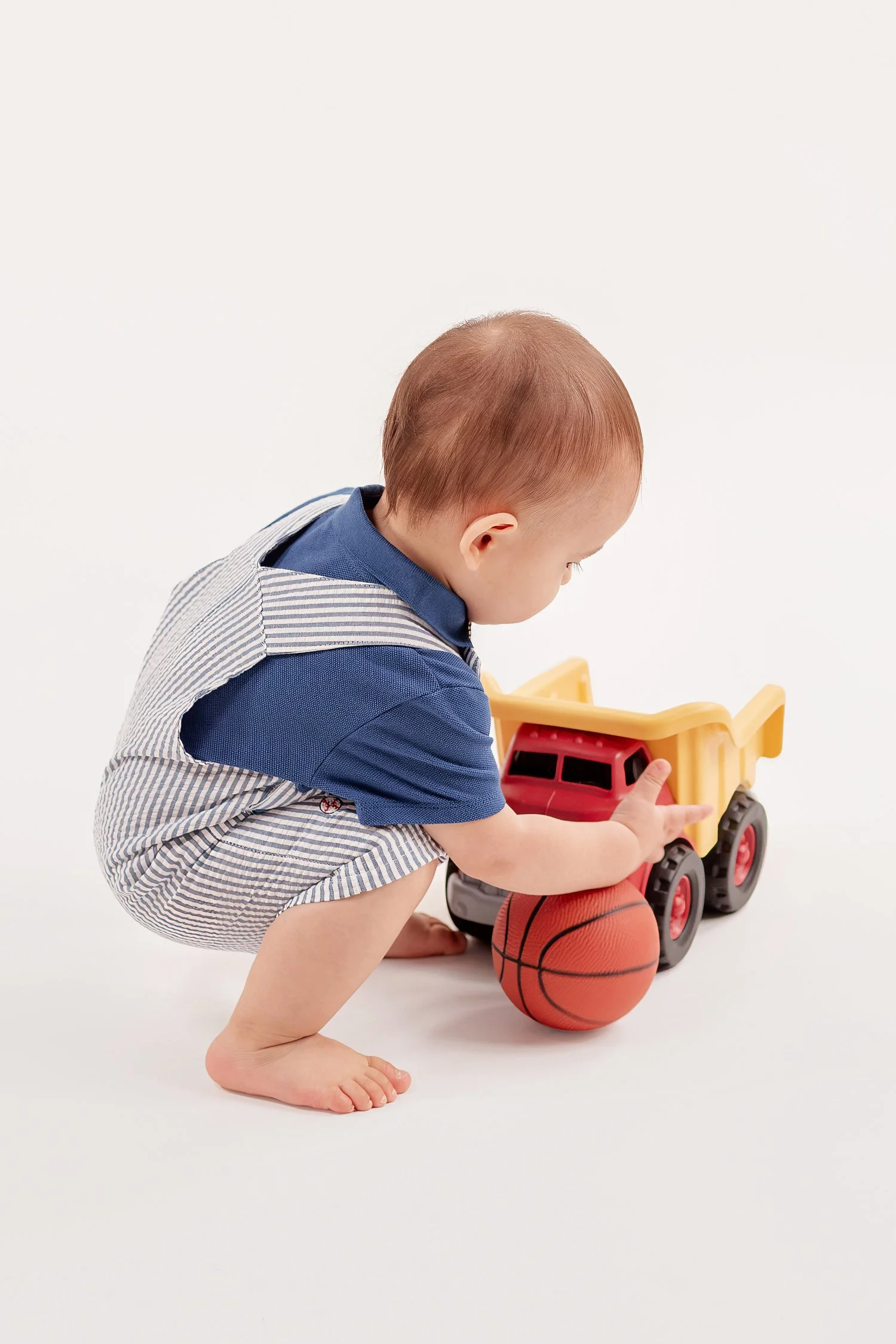 Winston crouching over the basketball beside his toy dump truck