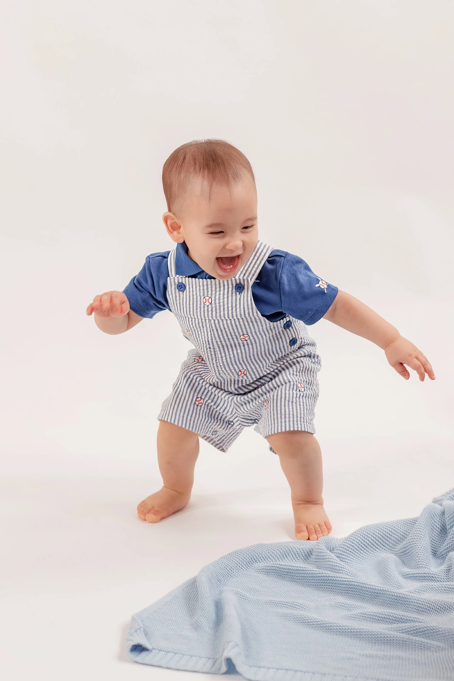 Winston grinning with his arms out beside his blue blanket