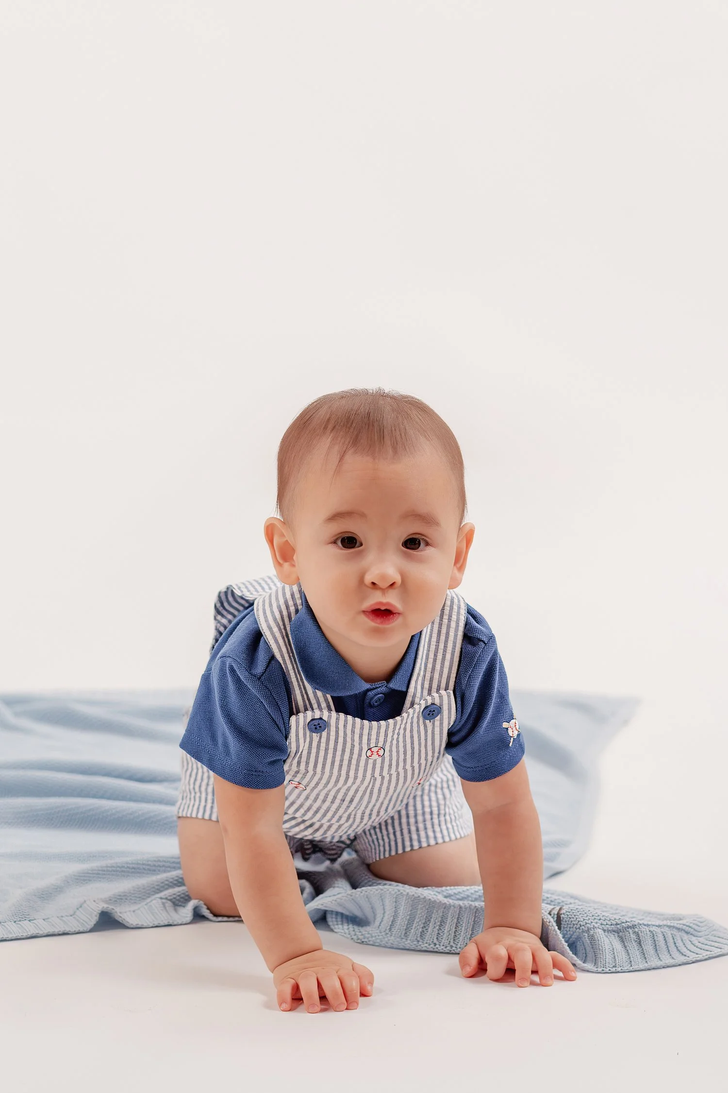 Winston on his hands and knees on the blue blanket