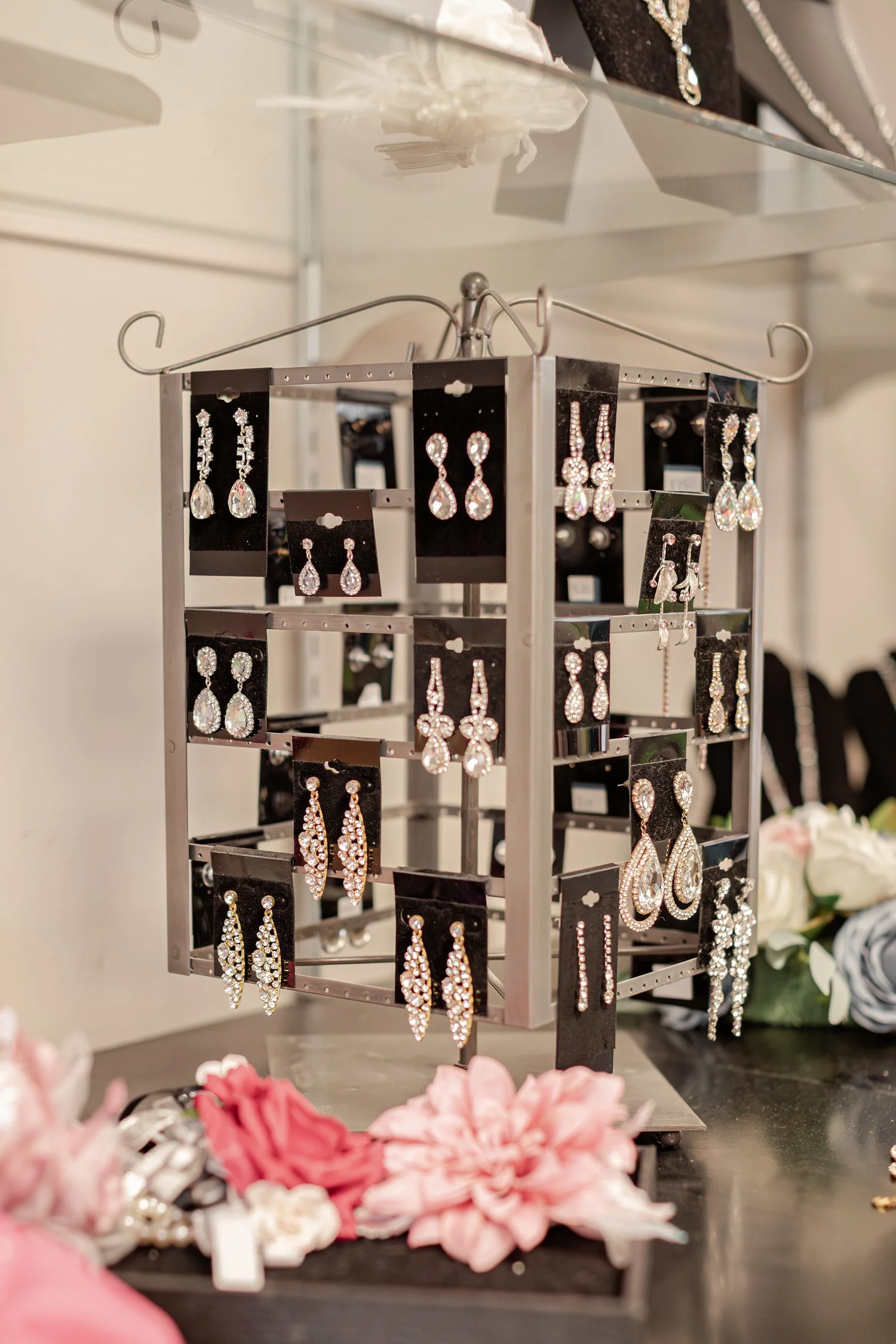 Rhinestone earrings behind pink and cream fabric flowers, brand photos for H&H New Creations Boutique in Bolivar MO