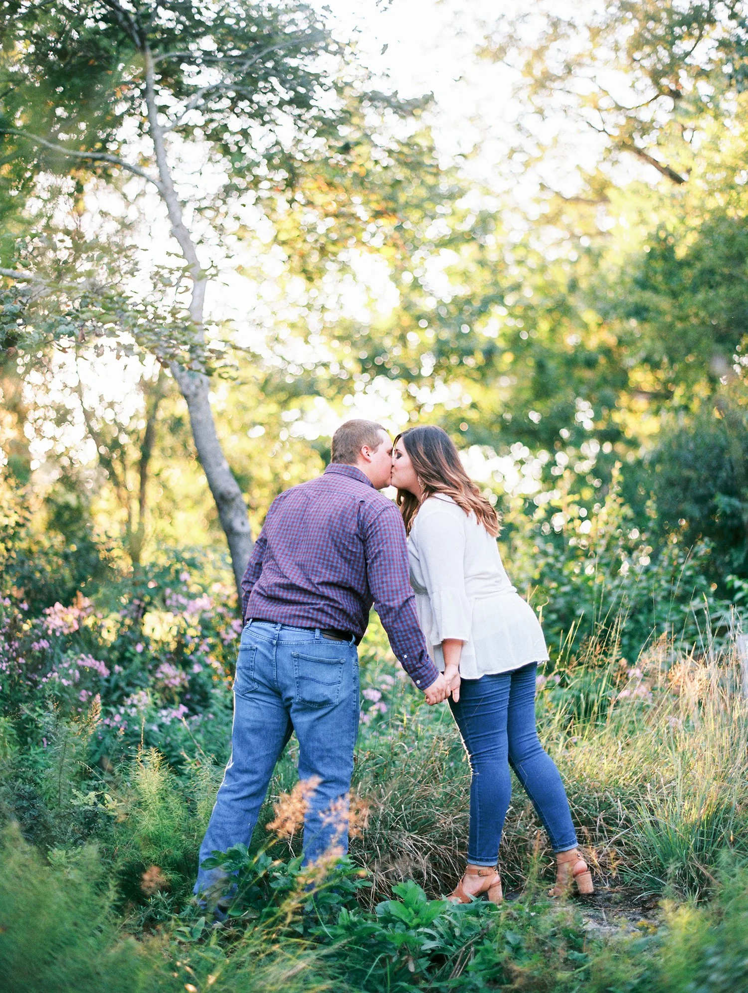 Sam and Mike holding hands and kissing in tall grass, Jordan Brittley Studio, Bolivar MO.