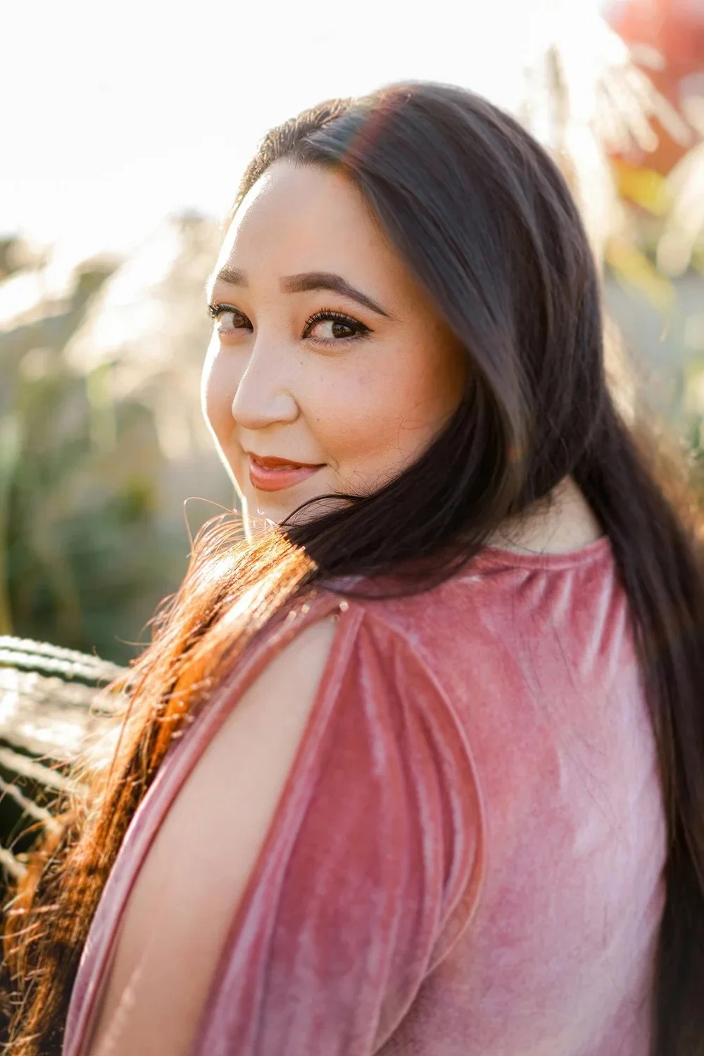 A senior looks back over her shoulder in a pink velvet top.