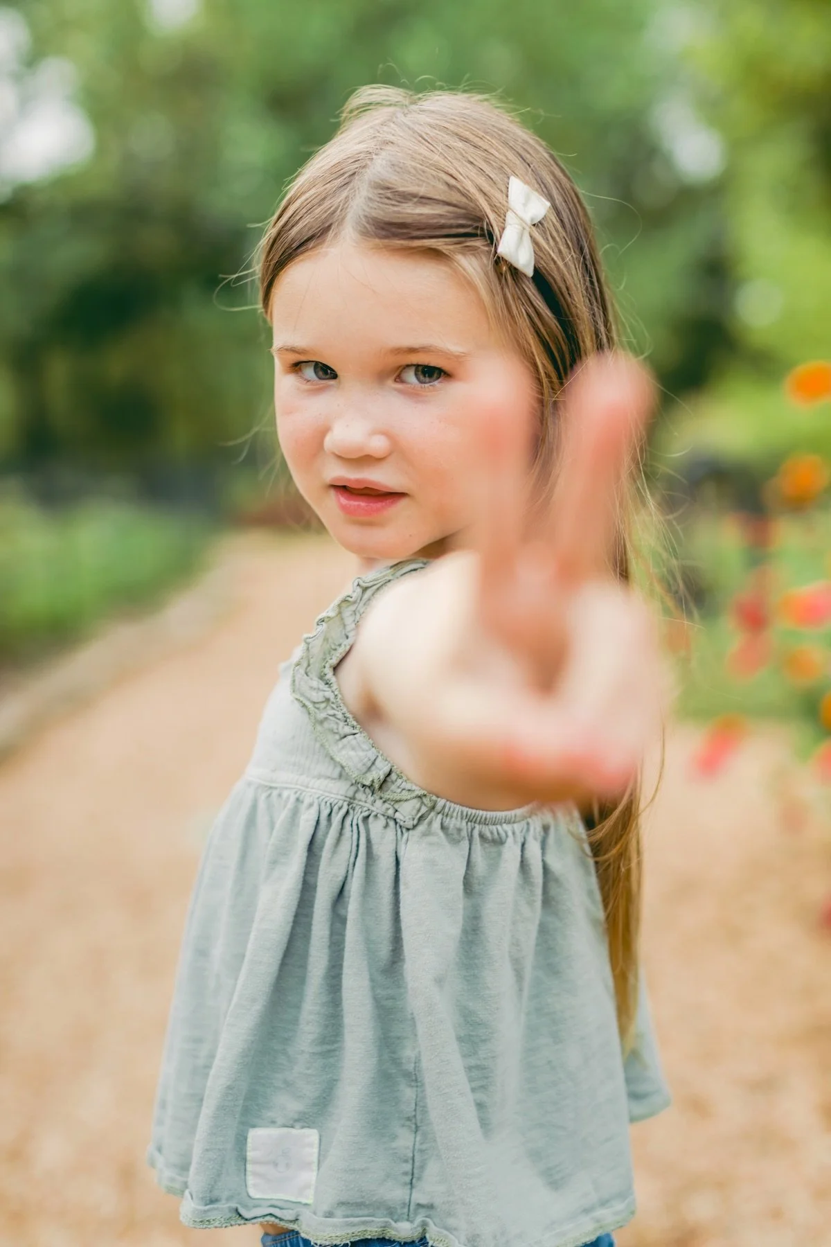 A girl wearing a small cream hair bow during an outdoor photo session