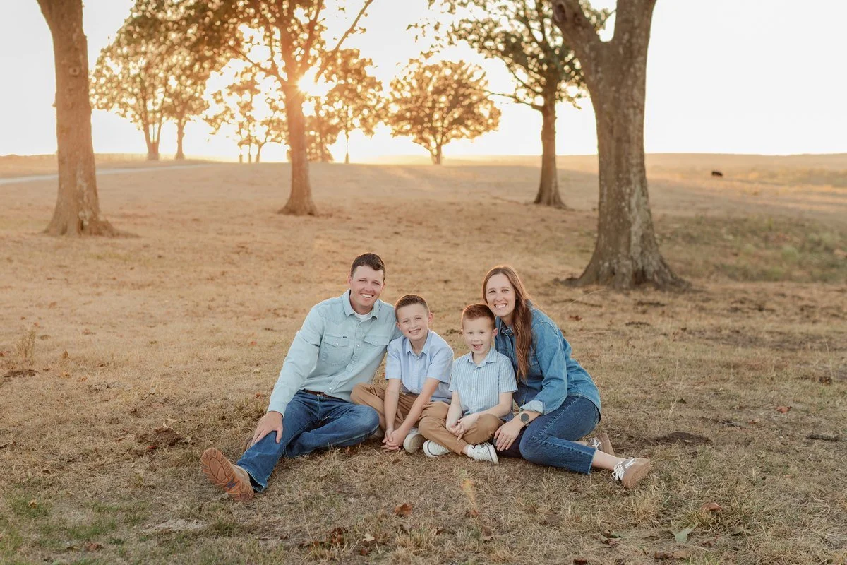 Family sitting together outdoors in denim, blue shirts, and tan pants.