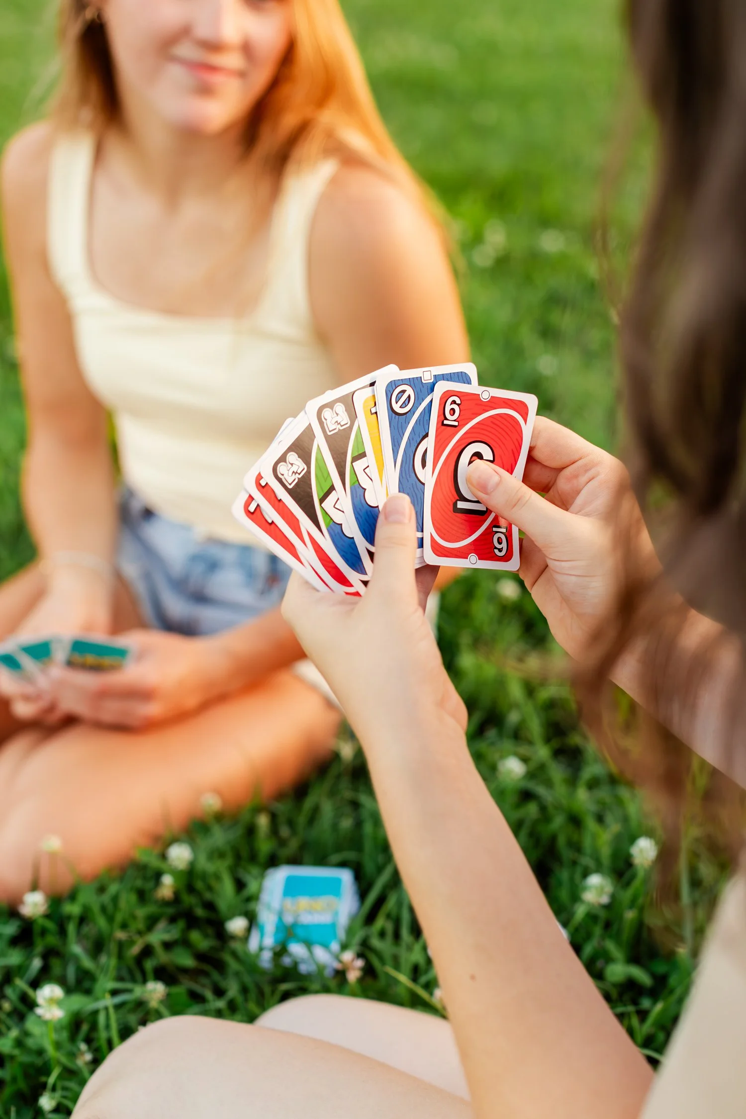 Friends hold Uno cards while playing a game outside.