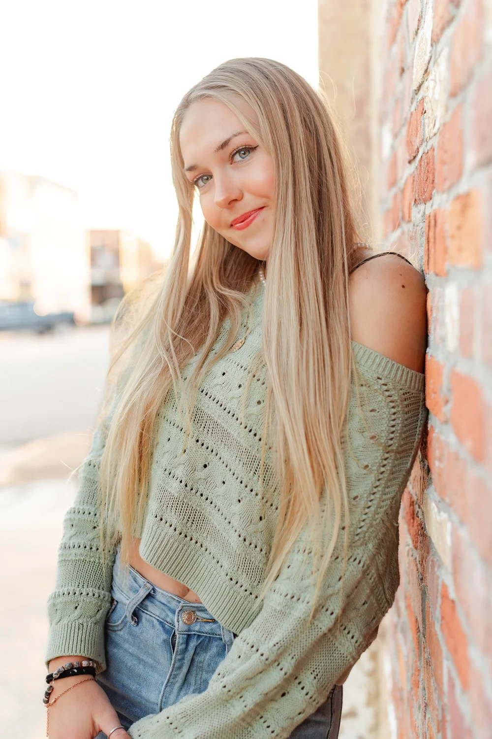 A senior leaning against a brick wall during her photo session