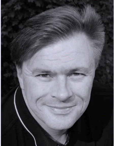 Mustavalkoinen valokuva Markusta, joka hymyilee ja katsoo suoraan kameraan.