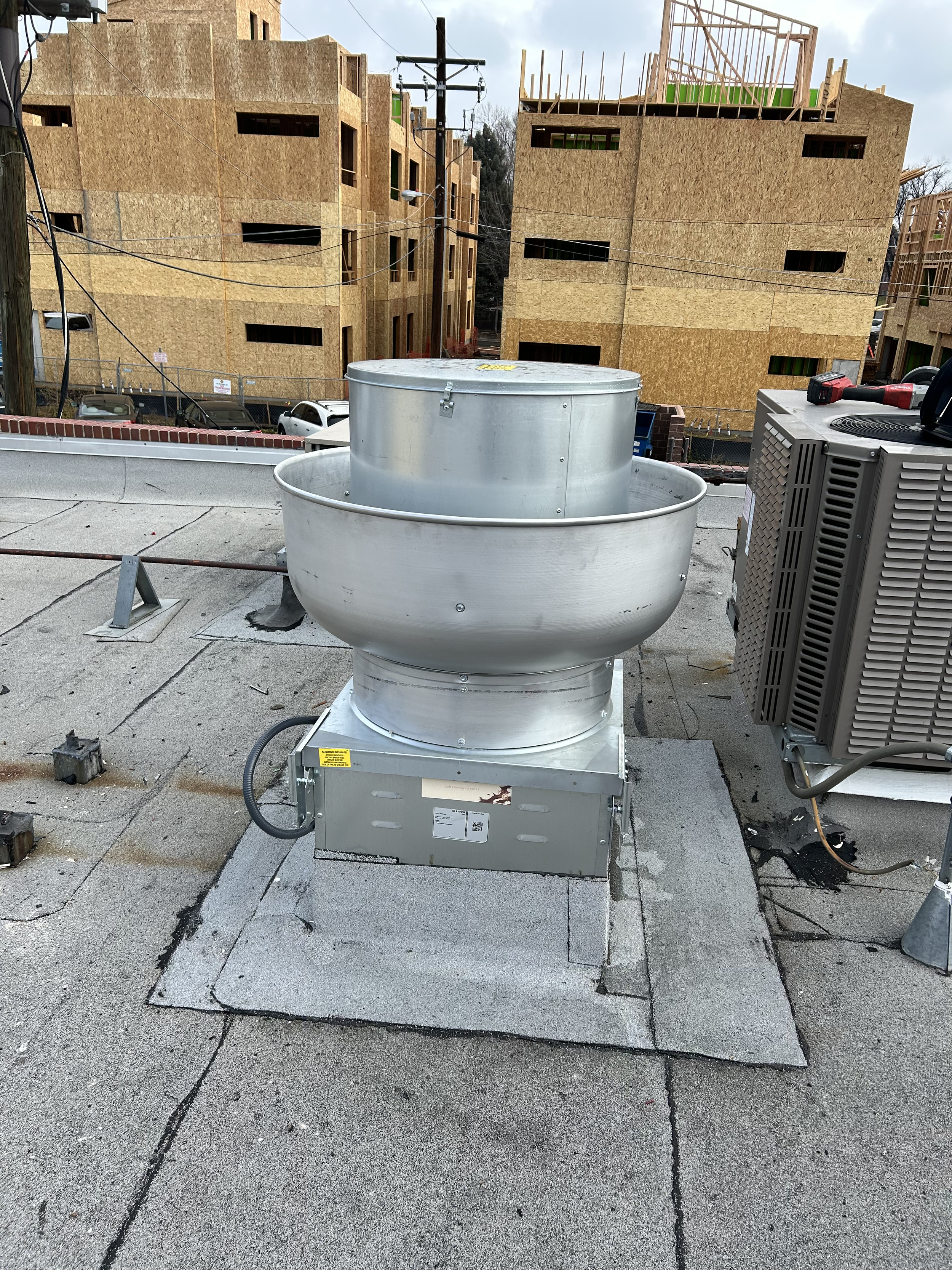 HVAC exhaust fan on a rooftop with construction site buildings in the background.