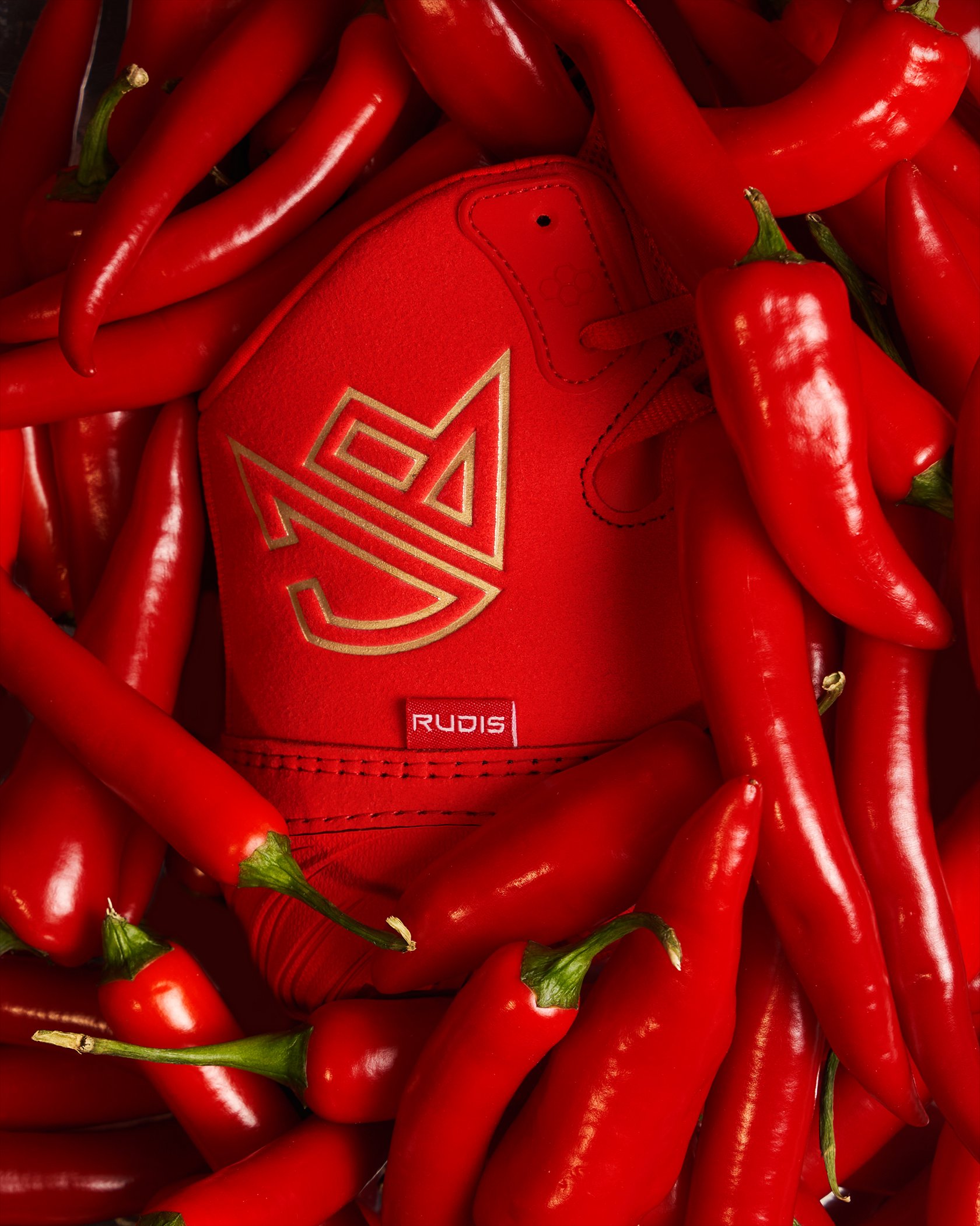 A red shoe with gold accents surrounded by red chili peppers.