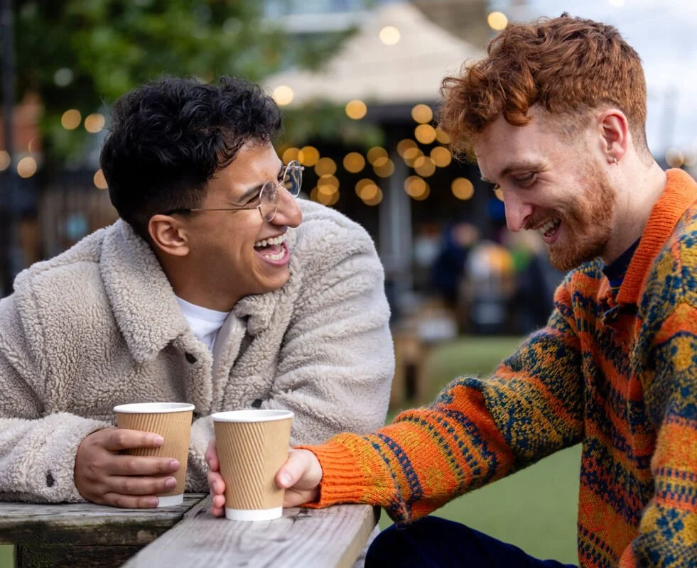 Two men sit together enjoying a conversation and laughing