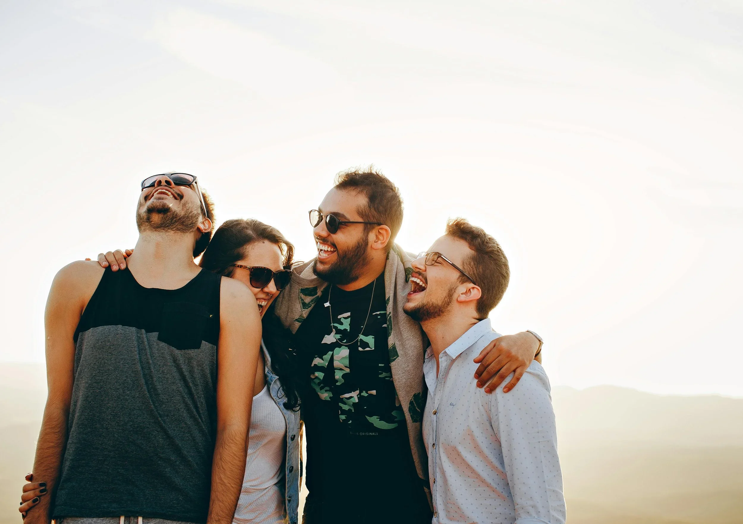 A group of 4 standing together laughing and smiling