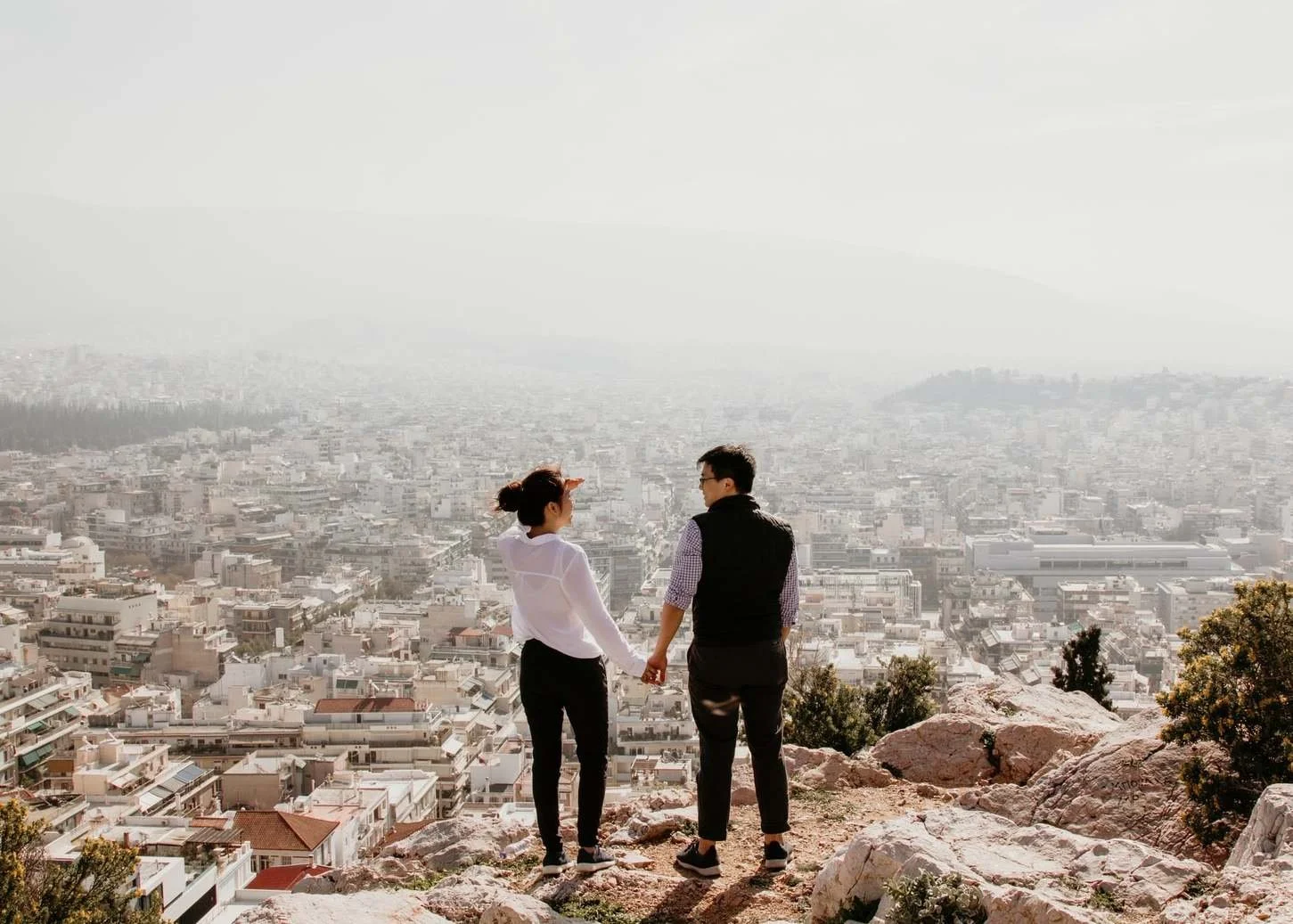 A couple holds hands while looking over a city from a height