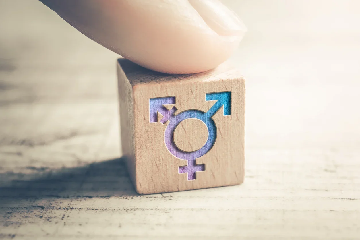 A small wooden block with the trans symbol
