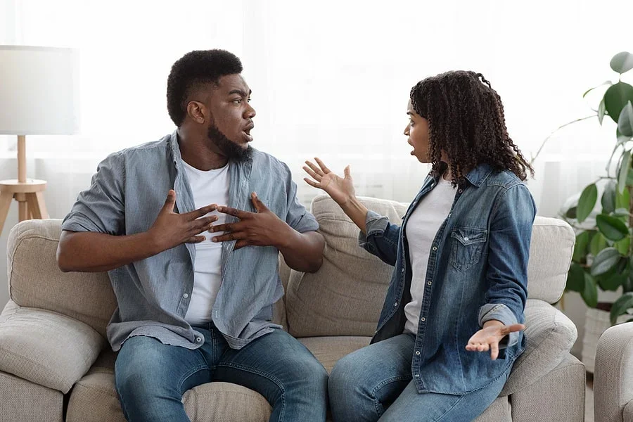 A couple sits on a couch in a heated argument
