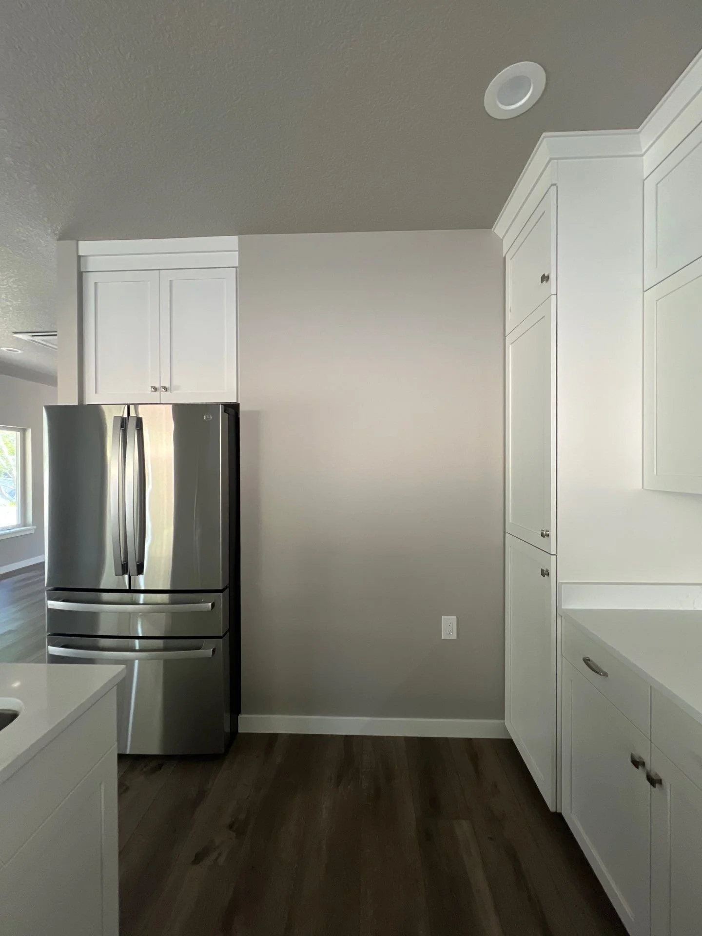 Kitchen corner with white cabinets, a stainless steel refrigerator, and dark wood flooring.