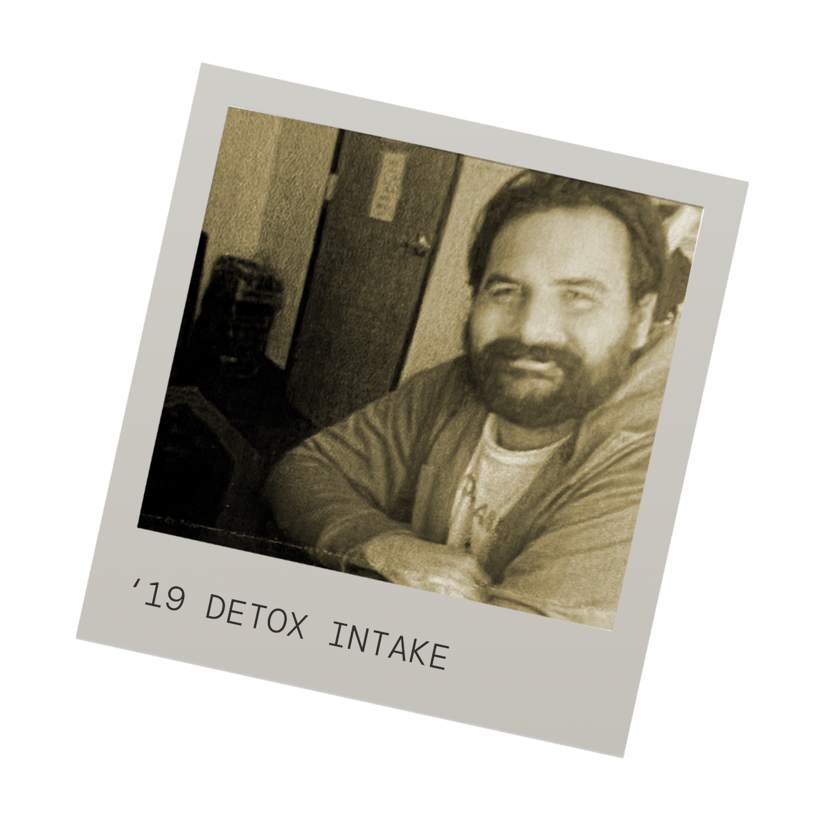 Polaroid-style photo of a man with a beard, sitting with arms crossed, in a room with a closed door and a trash can visible in the background. Caption reads '19 Detox Intake'