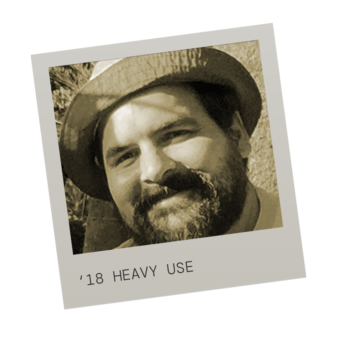 A sepia-toned photo of a man with a beard, wearing a straw hat, looking slightly to the side. Text at the bottom reads '18 HEAVY USE'.