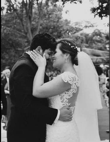 A romantic moment between a bride and groom at their wedding, with their foreheads touching and eyes closed.