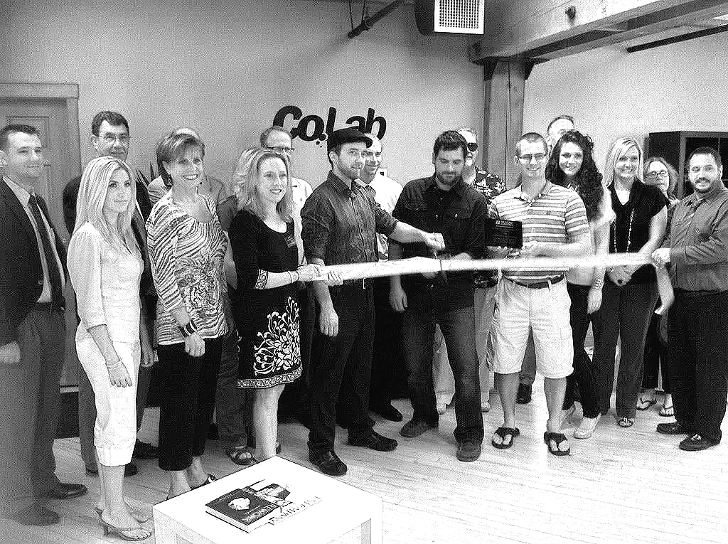 Group of people gathered indoors, participating in a ribbon-cutting event, with a