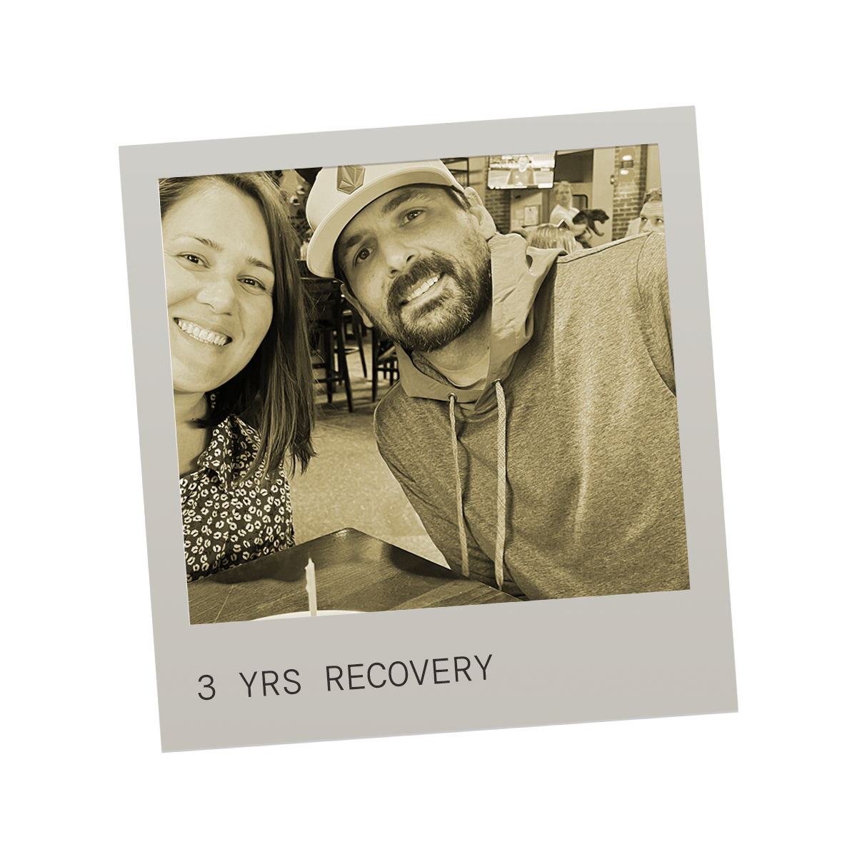 A sepia-toned photo of a smiling woman and man sitting together at a table in a restaurant, with the caption '3 YRS RECOVERY' at the bottom of the image.