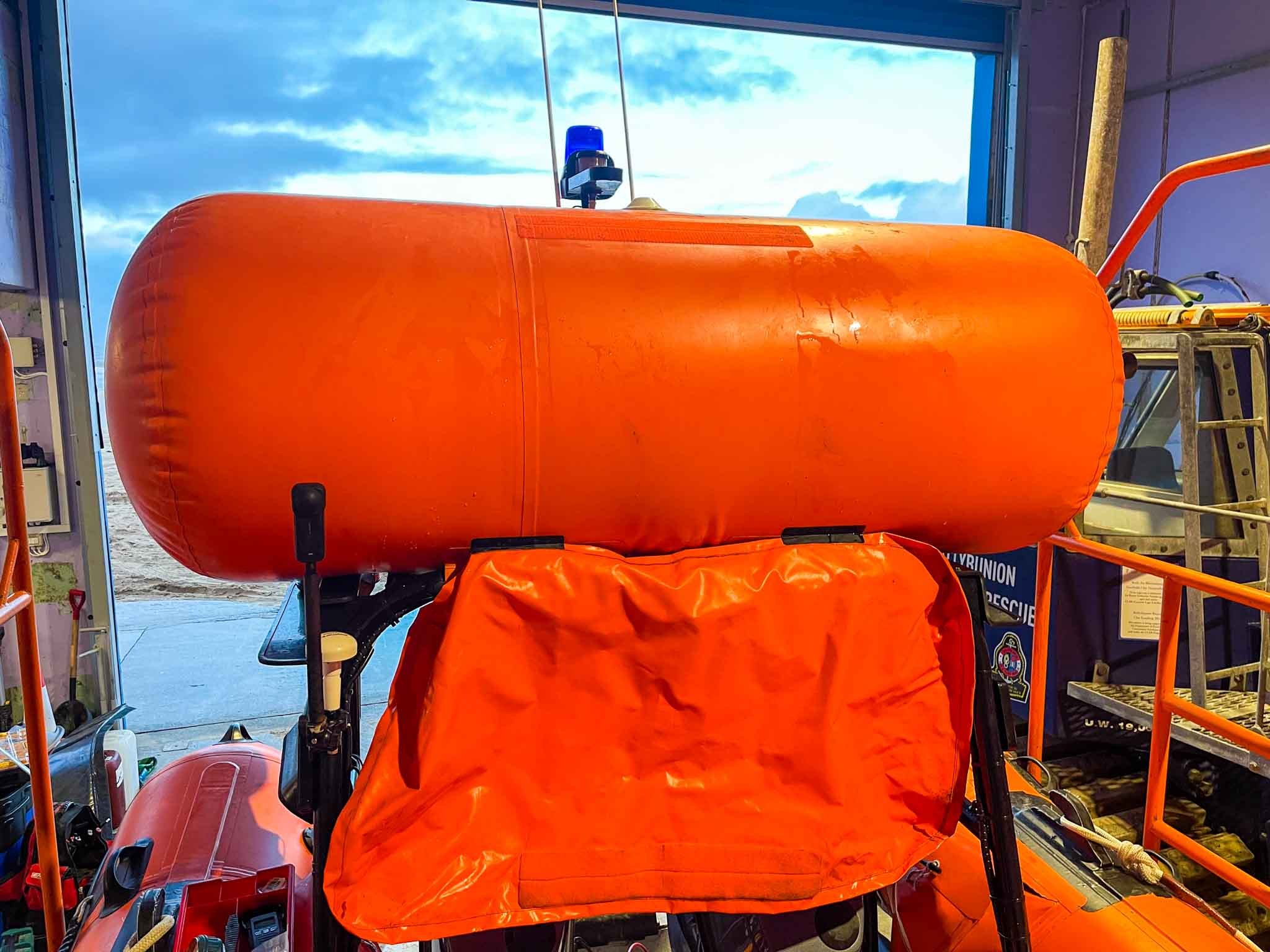 An orange rescue sled with a large orange oxygen tank attached, situated inside a rescue helicopter or aircraft.