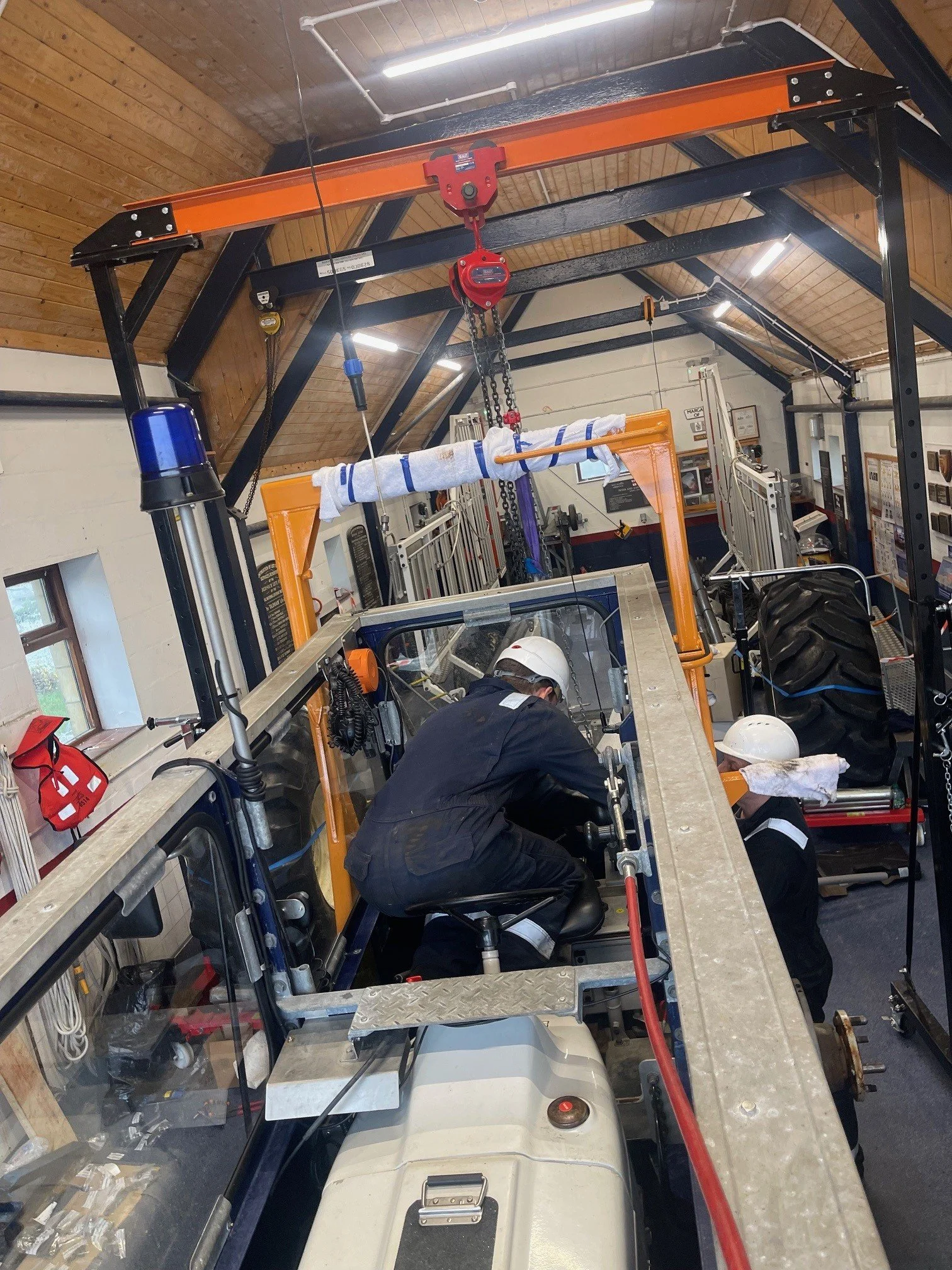 Four rescue team members wearing helmets and yellow jackets riding an orange boat on rough water.