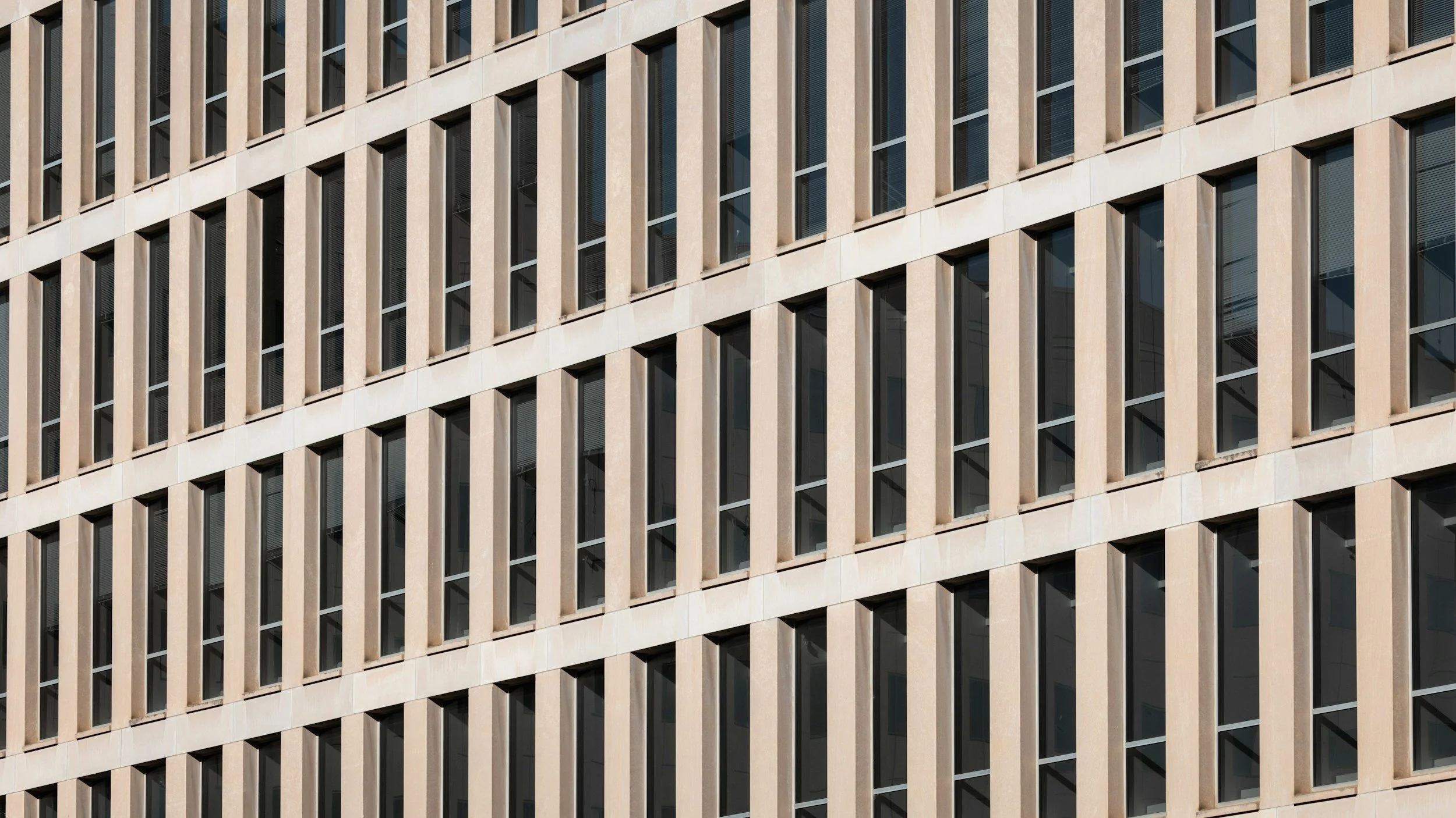 Close-up of a beige federal office building exterior with rows of dark windows, representing OPM headquarters and its new non-disclosure agreement for federal employees.
