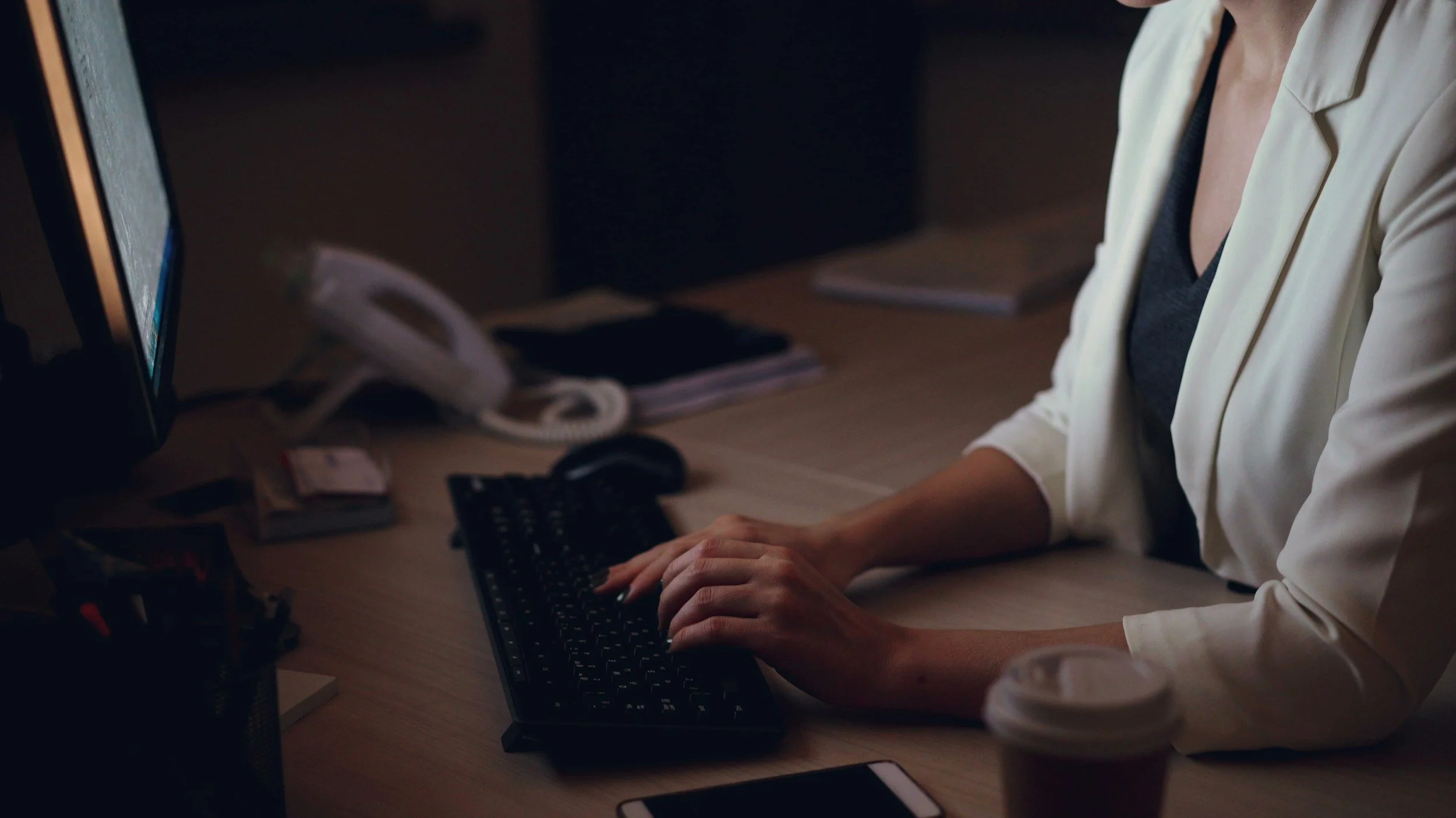Federal employee typing on a computer at their desk, representing the employee’s efforts to understand how OPM’s expanded suitability rules will impact their career.