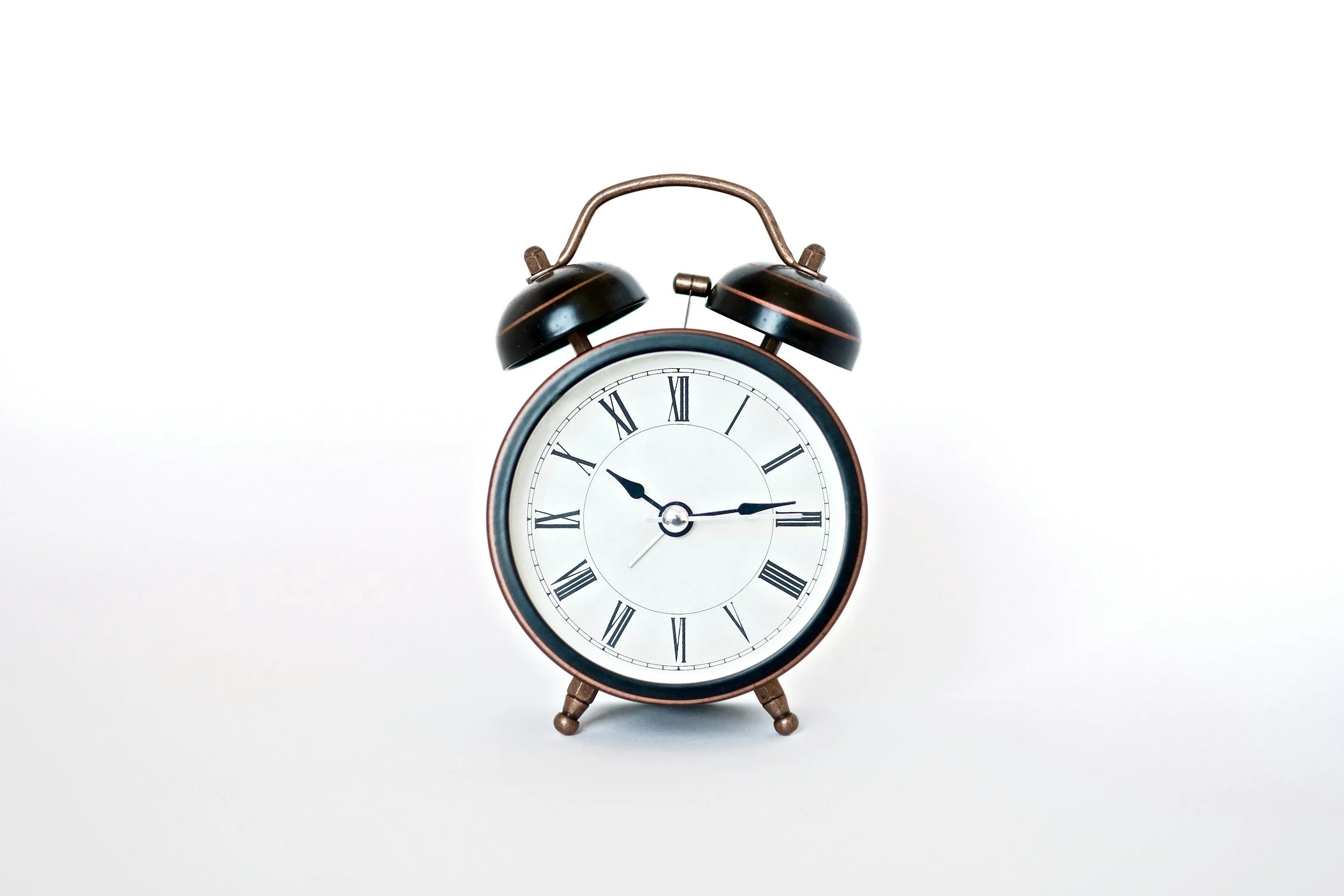 Old-fashioned black and brown clock with white face and roman numerals on a stark white background, symbolizing the deadlines that federal employees face when they have a workplace dispute.