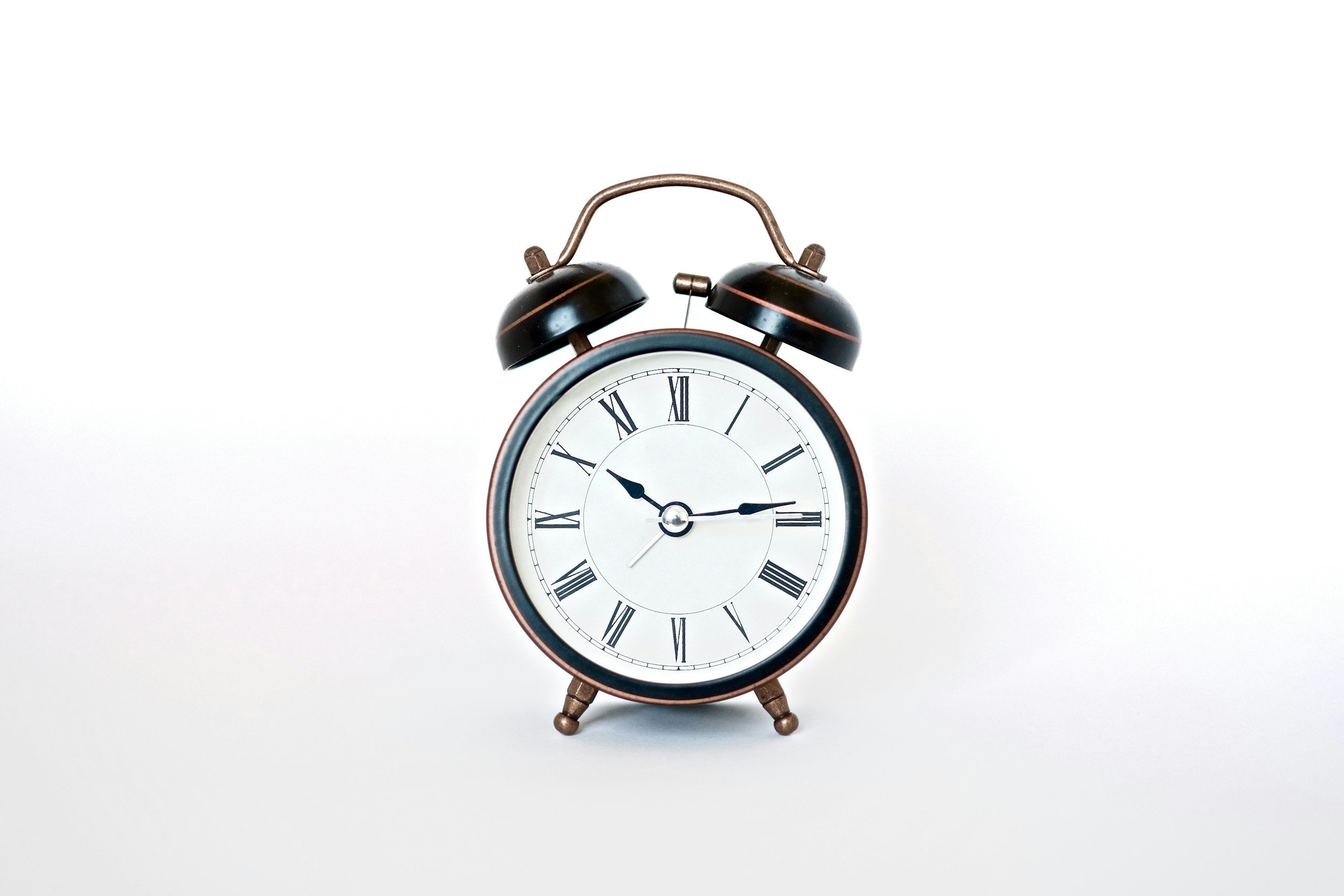 Old-fashioned black and brown clock with white face and roman numerals on a stark white background, symbolizing the deadlines that federal employees face when they have a workplace dispute.