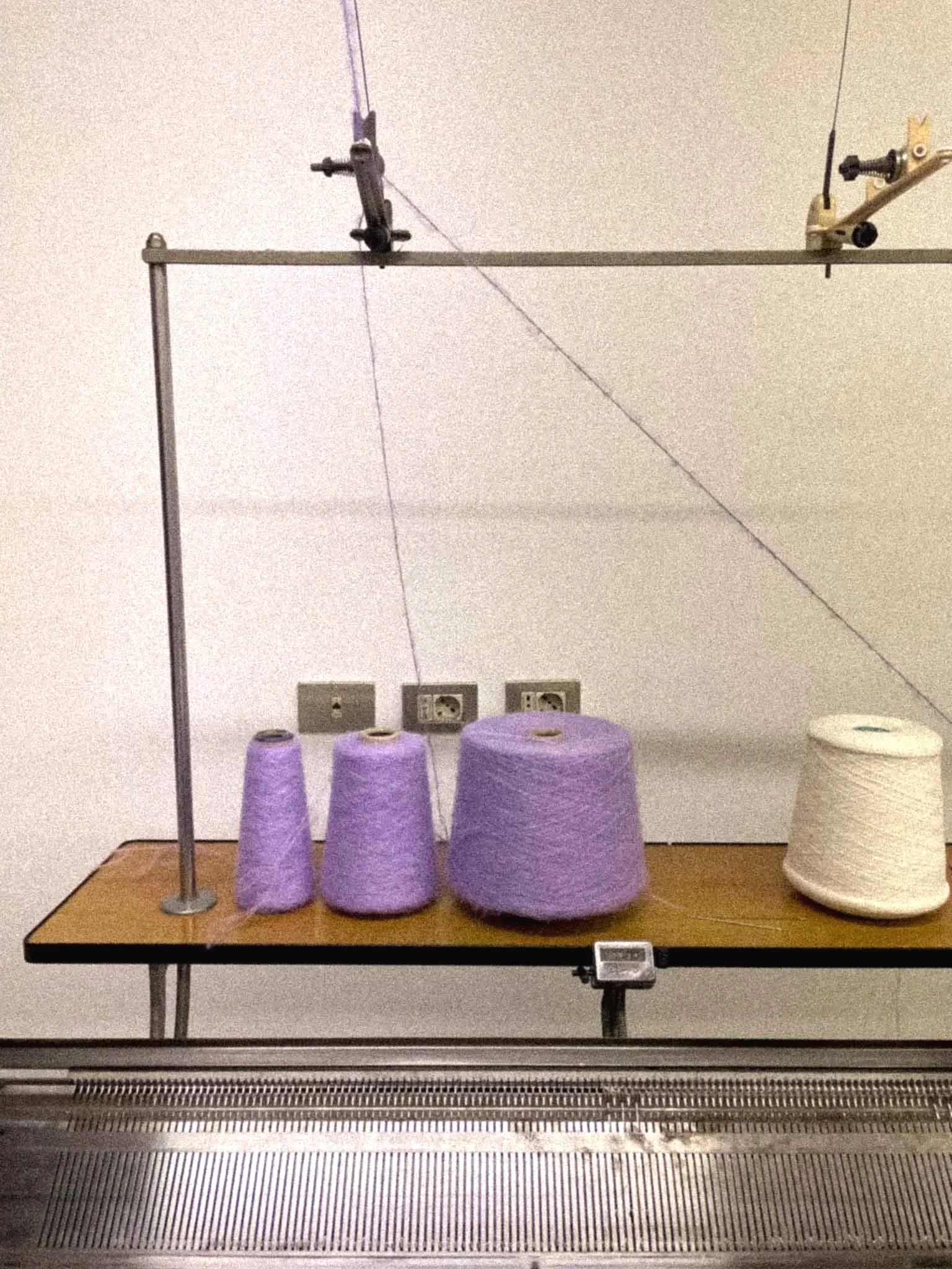 A treadmill holding four purple rolls of paper and a white roll of paper, with a treadmill conveyor belt in the foreground.