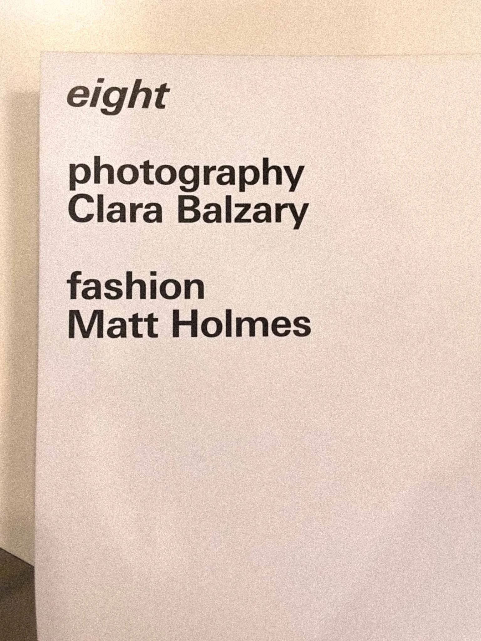Close-up of a sign with the words 'eight', 'photography', 'Clara Balzary', 'fashion', and 'Matt Holmes' printed on it.