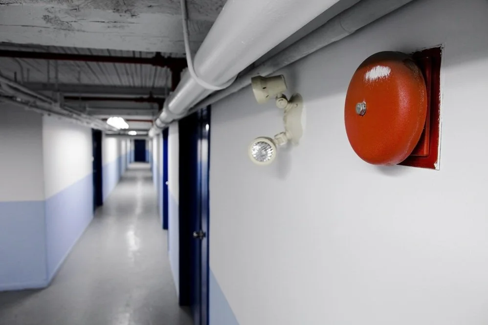 White Basement Hallway with Fire Alarm Bell and emergency lighting in foreground