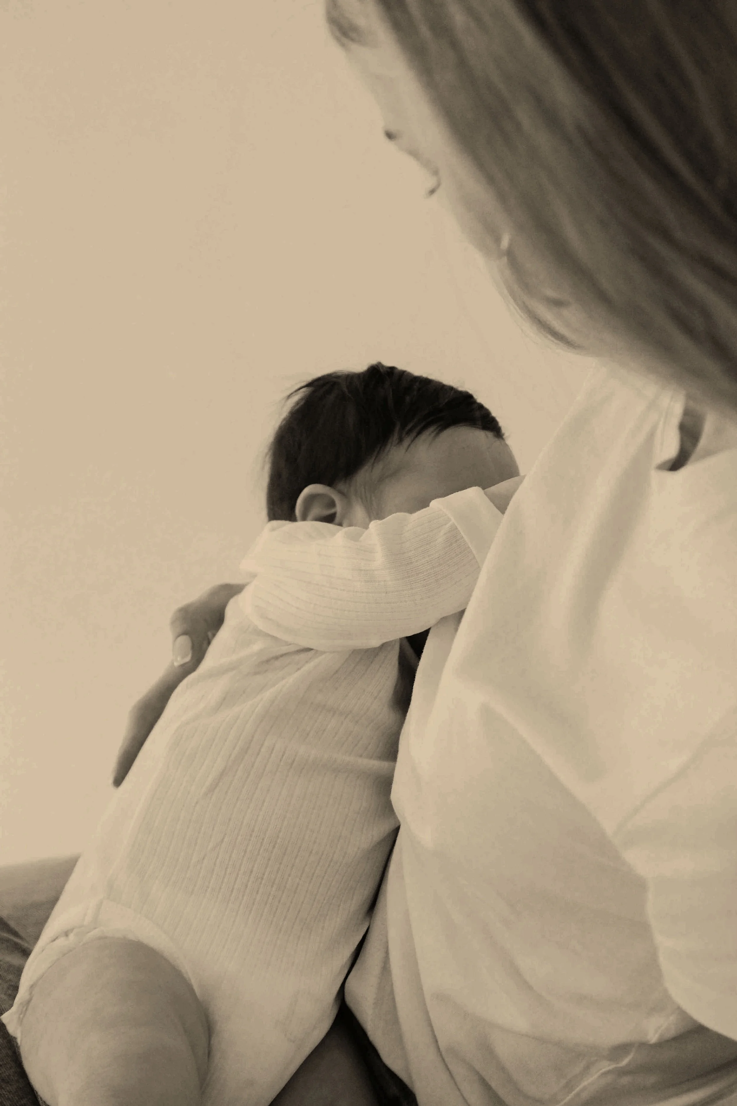 A young child hugging an adult, likely a parent, in a moment of comfort or affection. The image is in black and white.