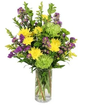 A colorful bouquet of flowers in a glass vase, including yellow daisies, purple statice, green carnations, and various greenery.