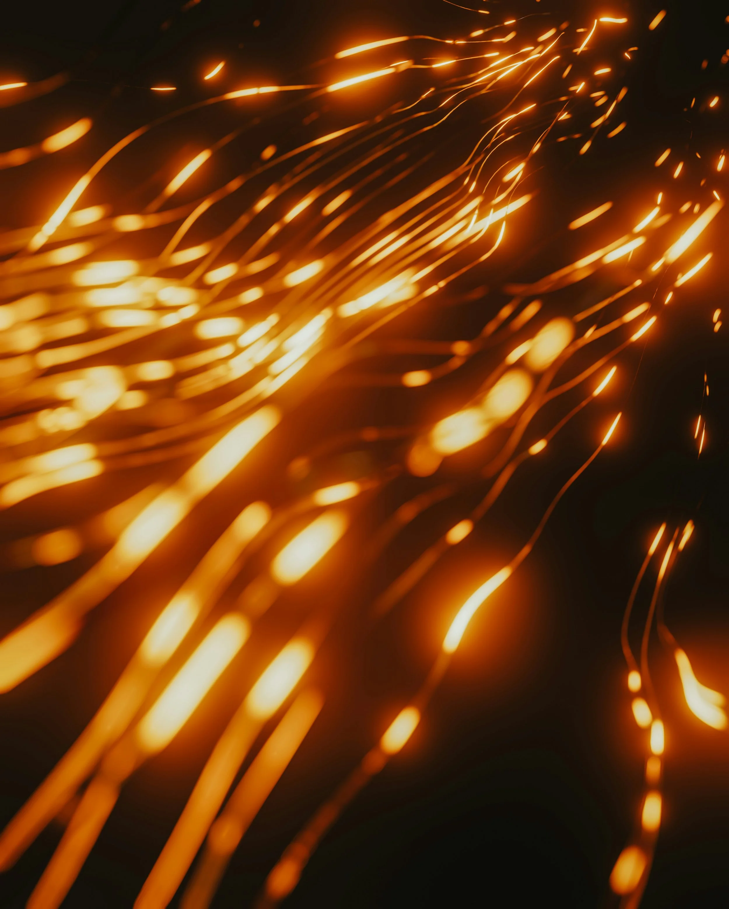 Close-up of bright orange sparks flying and glowing in the dark.