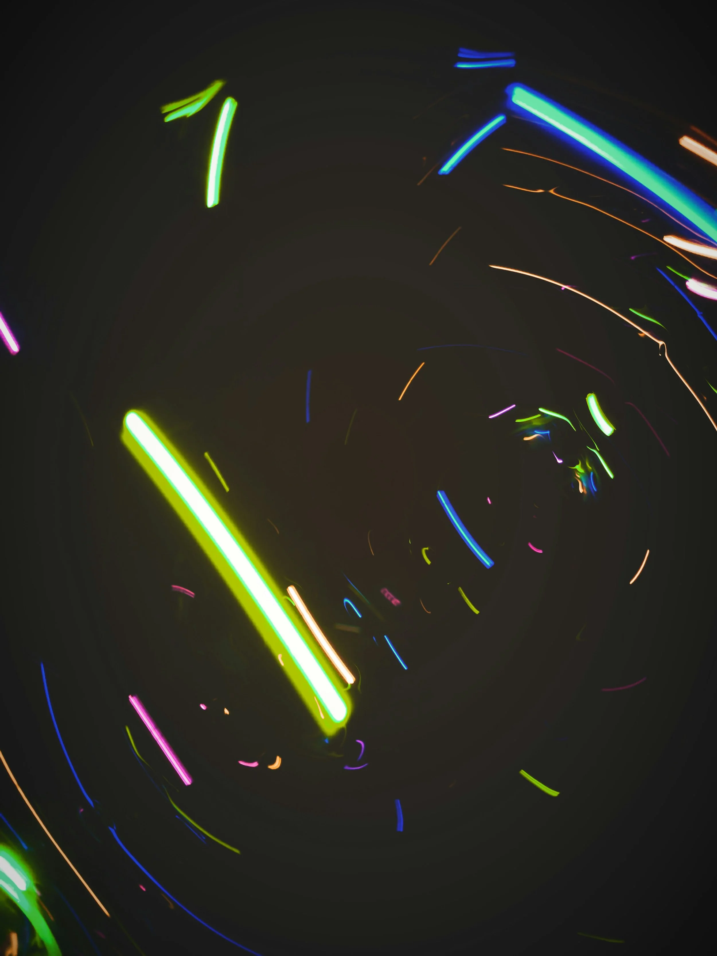 Long exposure photograph of colorful neon lights creating a spiral pattern against a dark background.