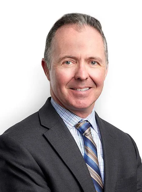 Business professional man in a suit with a dress shirt and tie, smiling, against a white background.