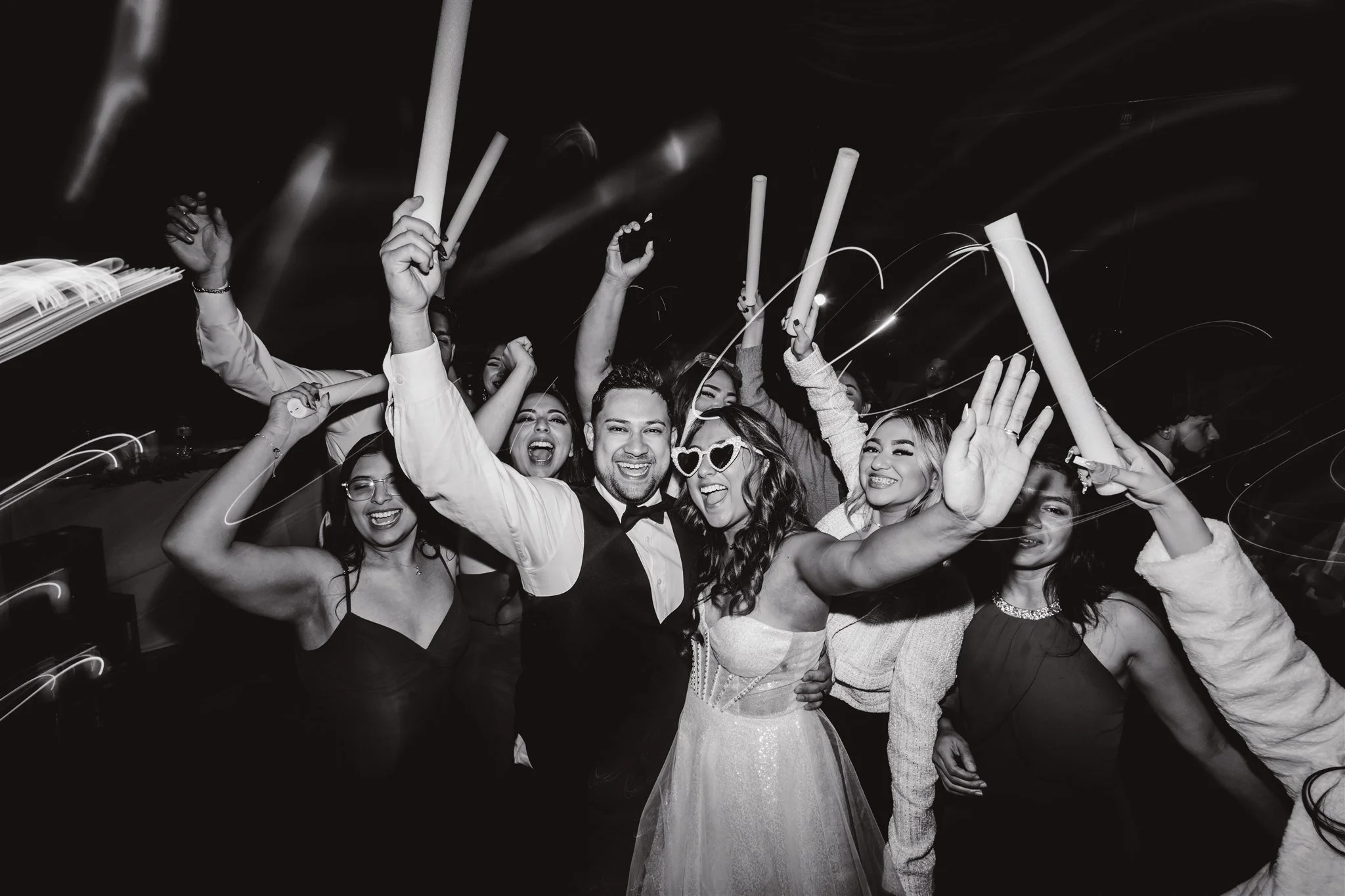 A group of happy people celebrating at a party, holding party blowers and decorated with festive accessories, smiling and having fun at their wedding
