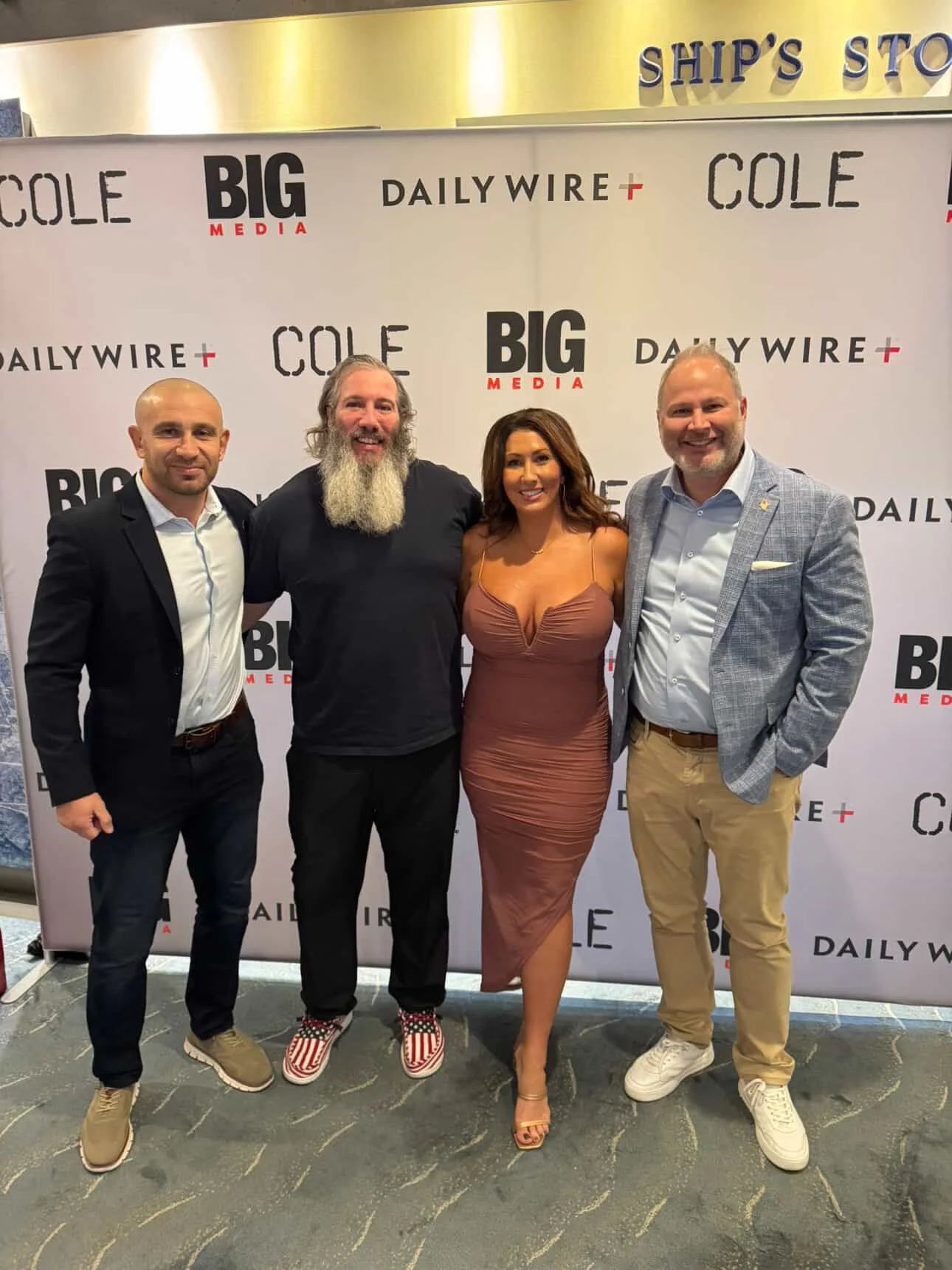 Four people standing together at a media event in front of a backdrop with the logos 'Big Media,' 'Daily Wire,' and 'Cole.' They are smiling and dressed in smart casual attire.