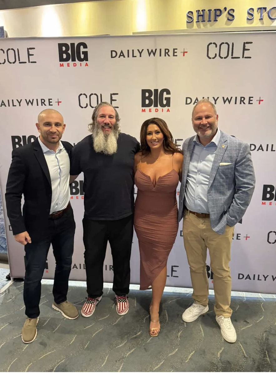 Four people standing in front of a backdrop with the logos of Big Media, Daily Wire, and Cole, smiling for a photo. The backdrop is white with black and red text.