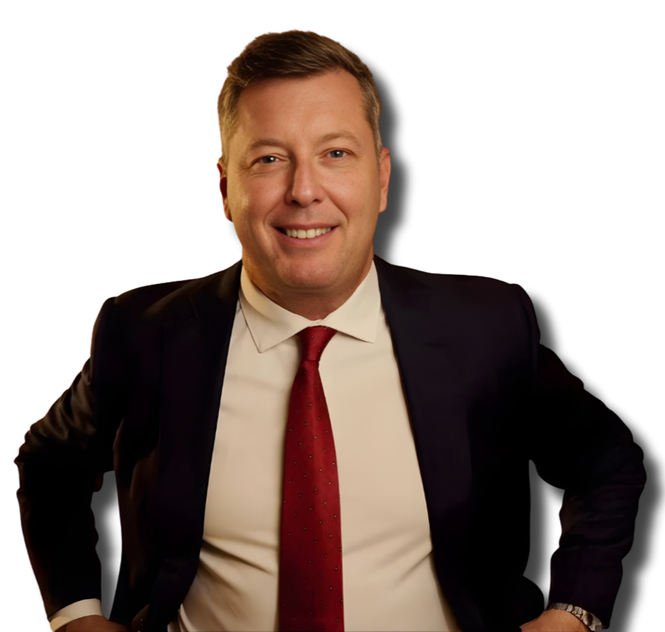 A smiling man in a business suit with a red tie, posing with one hand on his hip against a black background.
