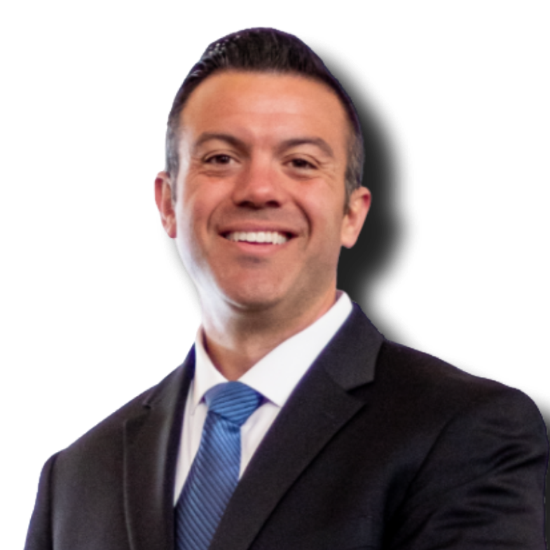 A man in a black suit, white shirt, and blue tie smiling, with short dark hair, against a solid black background.