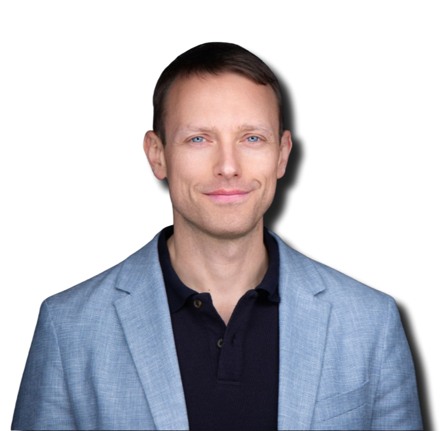 Portrait of a man with short brown hair and blue eyes, wearing a light grey blazer over a black polo shirt, smiling slightly against a black background.